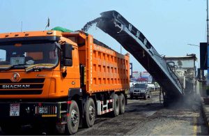 A milling machine loads asphalt material onto a truck during road construction work