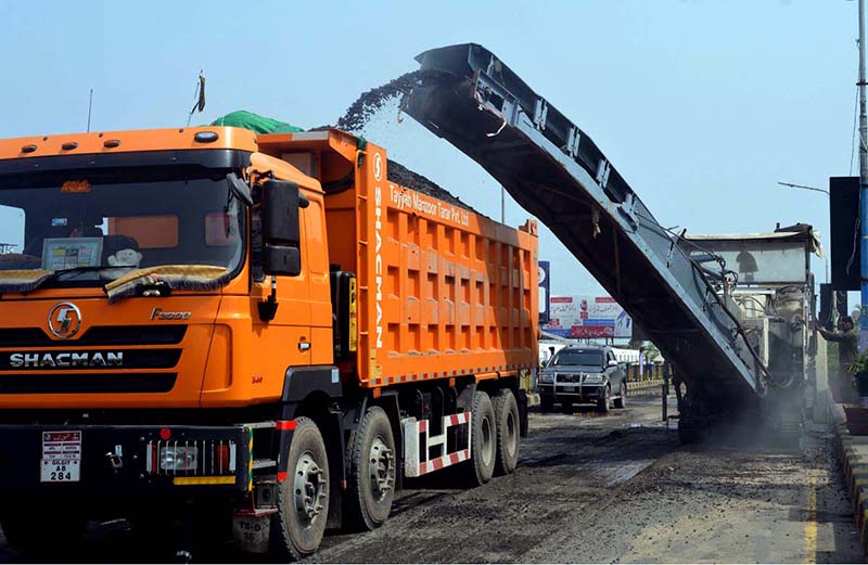 A milling machine loads asphalt material onto a truck during road construction work