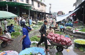 Vendors and customers throng a busy vegetable market, as the supply of fresh produce including cucumbers, tomatoes, carrots and citrus fruits remains active despite heavy monsoon rains lashing the federal capital.