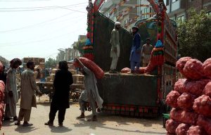 Daily-wage labourers unload onion sacks from a delivery truck at the Vegetable Market.