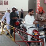 A petrol pump employee verifies a token number from a mobile message presented by a motorist to confirm eligibility for subsidized fuel under the Prime Minister’s petrol relief package