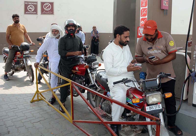 A petrol pump employee verifies a token number from a mobile message presented by a motorist to confirm eligibility for subsidized fuel under the Prime Minister’s petrol relief package