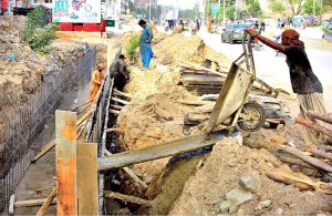 Labourers are busy with the construction work of a sewerage nallah along the road during development work in the city at Latifabad Unit No. 07