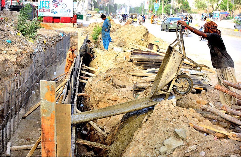 Labourers are busy with the construction work of a sewerage nallah along the road during development work in the city at Latifabad Unit No. 07