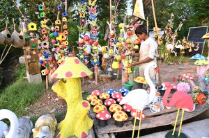 A boy displays handmade pink flamingo garden statues outdoors to attract customers