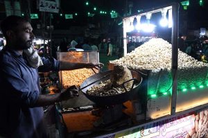 A vendor roasts and sells peanuts at Jinnah Bagh Chowk