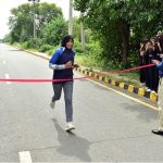 A female student of Government College University Faisalabad (GCUF) crosses the finish line to win the 10-kilometre race during International Sports Day at the university