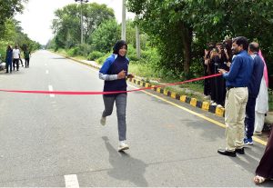 A female student of Government College University Faisalabad (GCUF) crosses the finish line to win the 10-kilometre race during International Sports Day at the university