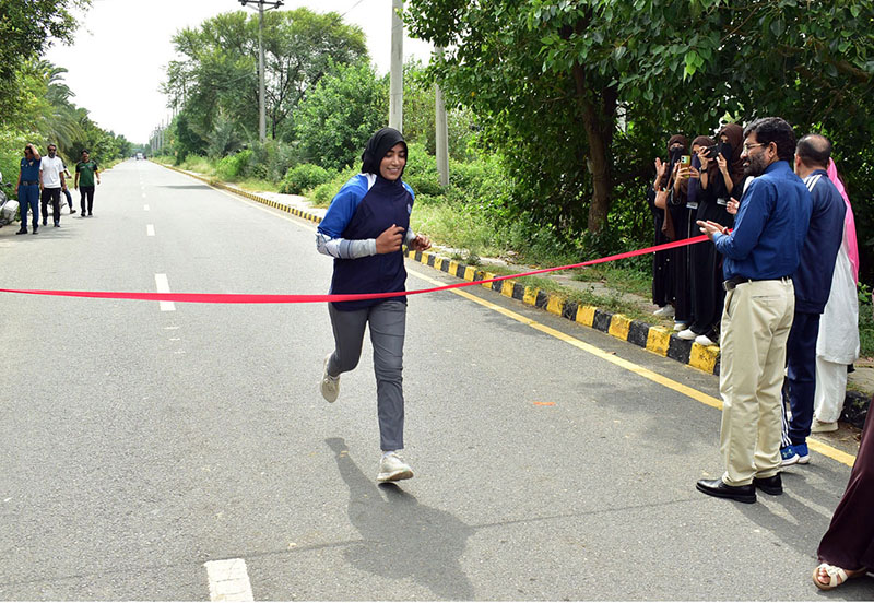 A female student of Government College University Faisalabad (GCUF) crosses the finish line to win the 10-kilometre race during International Sports Day at the university
