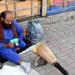A differently-abled vendor demonstrates a toy bubble gun for sale at the H-9 weekly bazaar