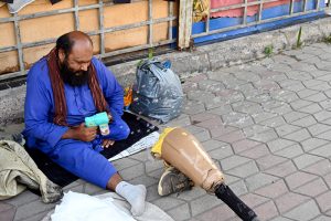 A differently-abled vendor demonstrates a toy bubble gun for sale at the H-9 weekly bazaar