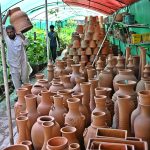 Vendor arranging and displaying plant pots to attract customers at H-9 local nursery in the federal capital