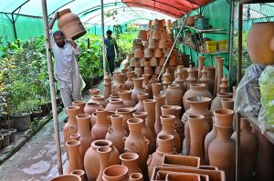 Vendor arranging and displaying plant pots to attract customers at H-9 local nursery in the federal capital