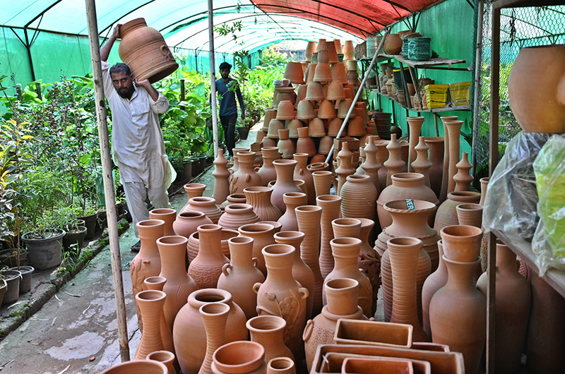 Vendor arranging and displaying plant pots to attract customers at H-9 local nursery in the federal capital