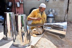 A worker busy in preparing the steel buckets at his workplace.