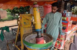 A vendor prepares traditional sardai, a refreshing summer drink, at his roadside setup to attract customers.
