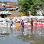 Workers washing empty plastic bags in the canal for reuse