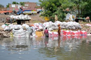 Workers washing empty plastic bags in the canal for reuse