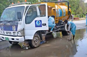WASA workers are busy removing water accumulated on the road with a suction machine