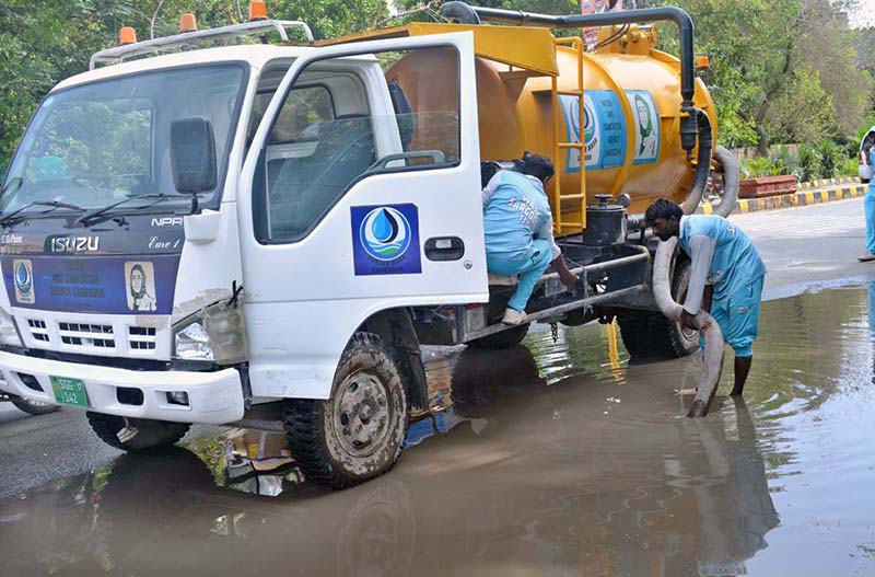 WASA workers are busy removing water accumulated on the road with a suction machine