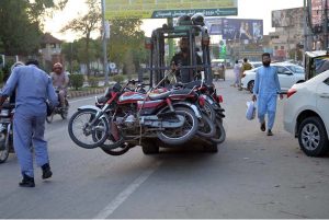 A forklift-mounted traffic lifter hauls away wrongly parked motorcycles as part of an enforcement drive