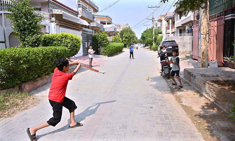 Children are playing cricket in a street at Canal Park