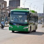 The electric bus in the city moves along a city road, offering commuters modern, eco-friendly, and comfortable public transport with advanced technology
