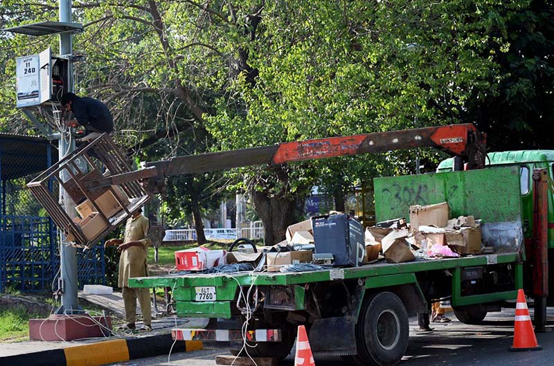 Technicians use a crane-mounted platform to install a Safe City camera on a pole at Aabpara Chowk in the Federal Capital