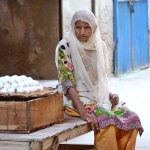 An elderly woman vendor waiting for customers to sell eggs at her roadside setup