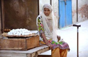 An elderly woman vendor waiting for customers to sell eggs at her roadside setup