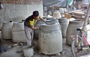 A skilled worker preparing traditional clay oven (tandoor) at his workplace.