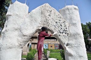 A worker is busy beautifying the entrance gate of the railway station park in an unconventional style.