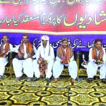 Grooms sitting on stage during a mass wedding ceremony organized by Jillani Welfare Foundation at Bagh-e-Mustafa Ground