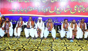 Grooms sitting on stage during a mass wedding ceremony organized by Jillani Welfare Foundation at Bagh-e-Mustafa Ground
