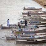 A large number of boats are parked on the bank of the Indus River at Al-Manzar picnic point