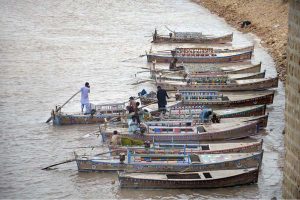 A large number of boats are parked on the bank of the Indus River at Al-Manzar picnic point