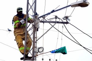 A HESCO worker removes an illegal electricity hook connection during an anti-theft drive in the Old Subzi Mandi area.