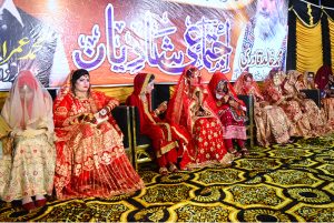 Grooms sitting on stage during a mass wedding ceremony organized by Jillani Welfare Foundation at Bagh-e-Mustafa Ground