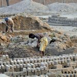 Laborers work in grueling conditions at a local brick kiln, mixing clay and shaping raw bricks to earn their daily livelihood
