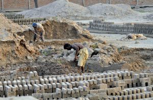 Laborers work in grueling conditions at a local brick kiln, mixing clay and shaping raw bricks to earn their daily livelihood