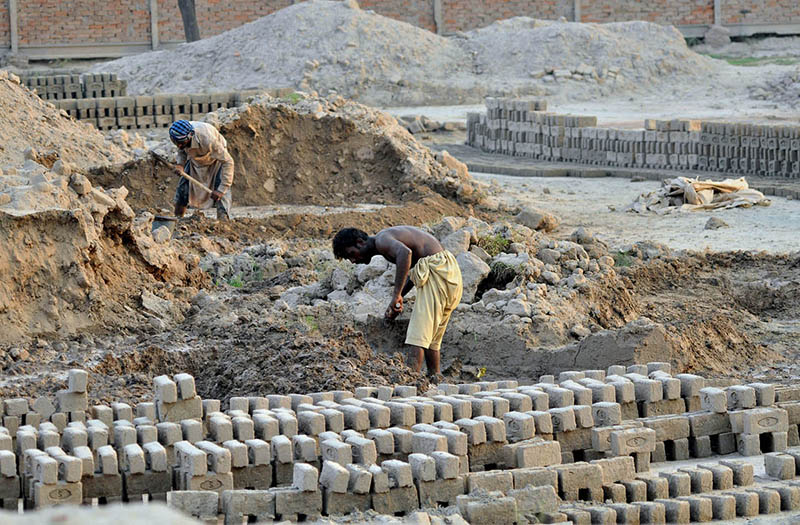 Laborers work in grueling conditions at a local brick kiln, mixing clay and shaping raw bricks to earn their daily livelihood