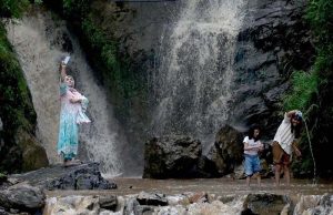A woman takes a selfie while others splash in the cool waters at the base of the magnificent Sabri Waterfall.