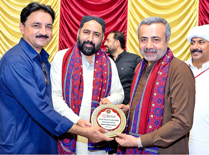 Chief Guest and PPP leader Sardar Tariq Anwar Khan Siyal, along with renowned Sindhi poet Gulfam Gul Sangi, presents a shield to APP Larkana photographer Nadeem Akhtar Soomro in recognition of his outstanding coverage of the Sindh Theatre Festival 2026 during the closing ceremony at Z.A. Bhutto Open-Air Theatre, Arts Council Larkana