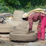 A woman making a traditional clay oven (tandoor) at her workplace