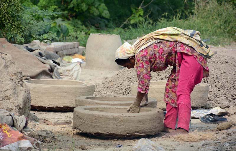 A woman making a traditional clay oven (tandoor) at her workplace