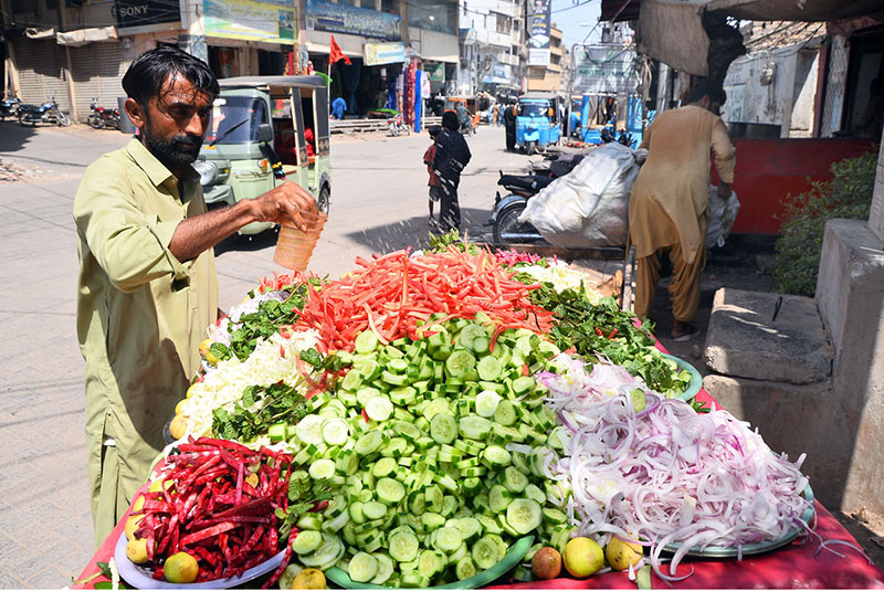 A handcart vendor displays fresh salad to attract customers along Saddar Road