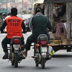 A motorcyclist pushes a Rescue 1122 motorcycle at Club Chowk