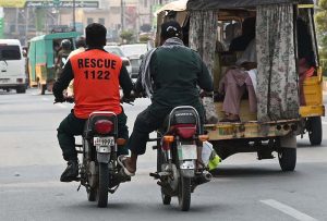 A motorcyclist pushes a Rescue 1122 motorcycle at Club Chowk