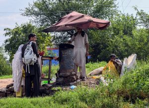 A couple buys roasted corn from a roadside vendor at a corn stall along a greenbelt in the federal capital.