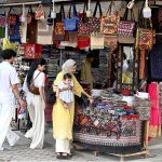 Visitors looking for handmade embroideries at a stall setup in Lok Virsa